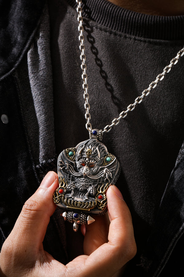 A gawu amulet held in the hand, on its chain