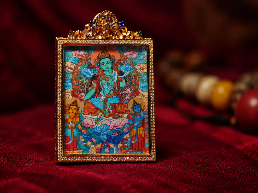 Close-up of a miniature Green Tara thangka with a decorative frame against burgundy fabric